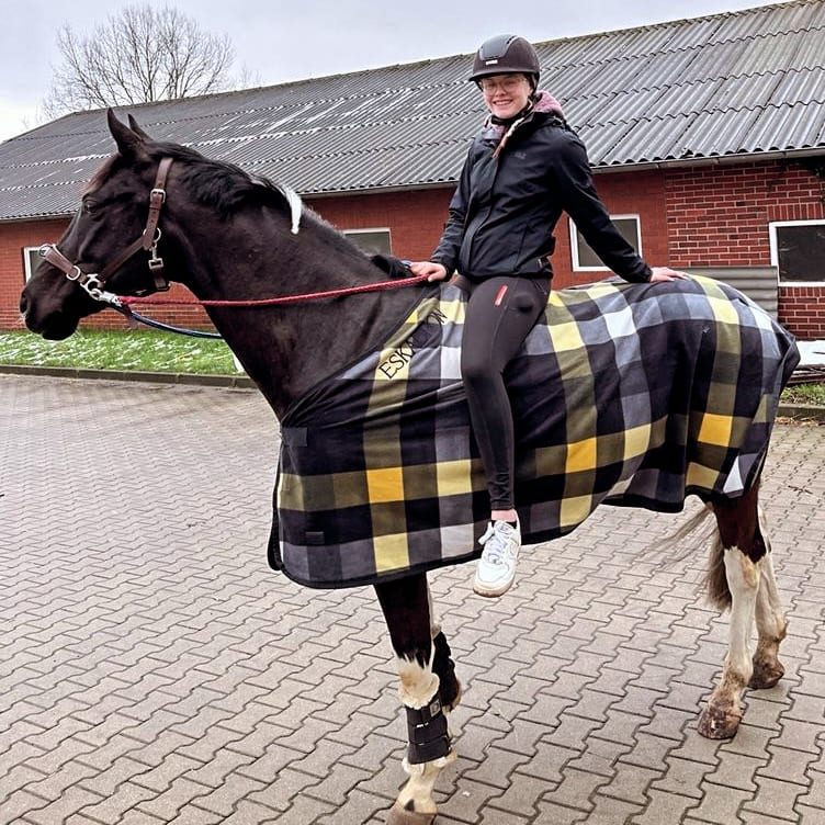 Glückliche Reiterin auf schwarzem Pferd – Harmonie zwischen Pferd und Reiterin nach Sattelberatung